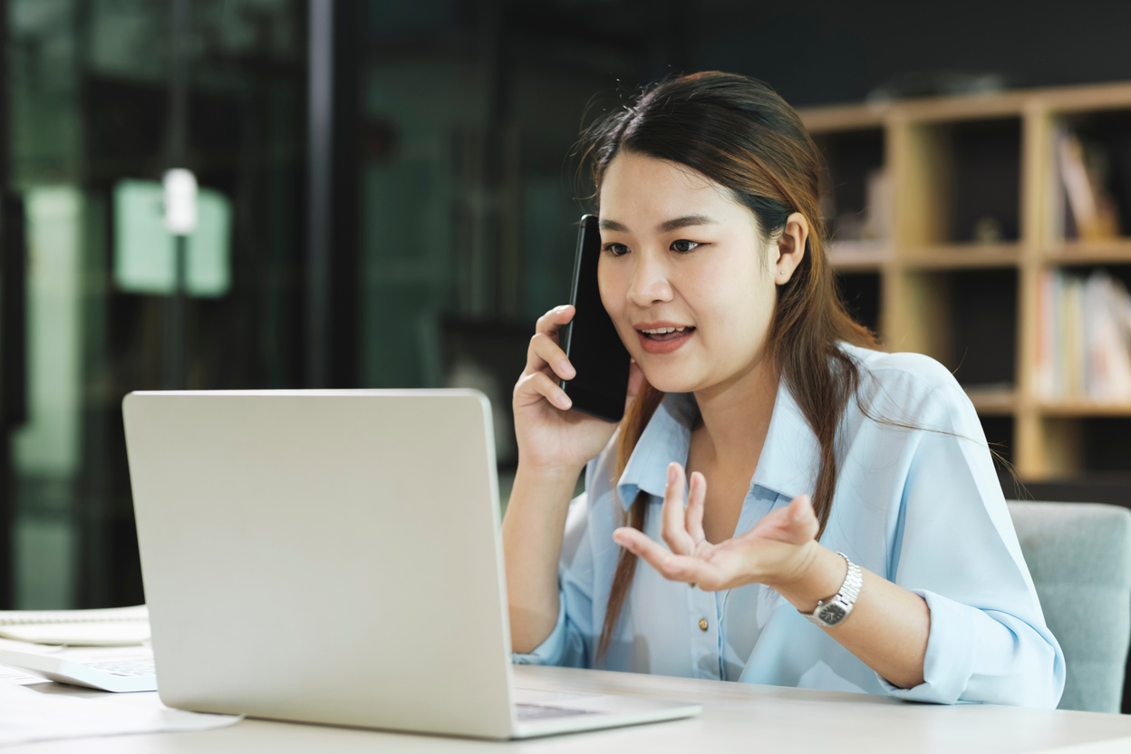 Smiling businesswoman talking on smartphone while waiting client in office